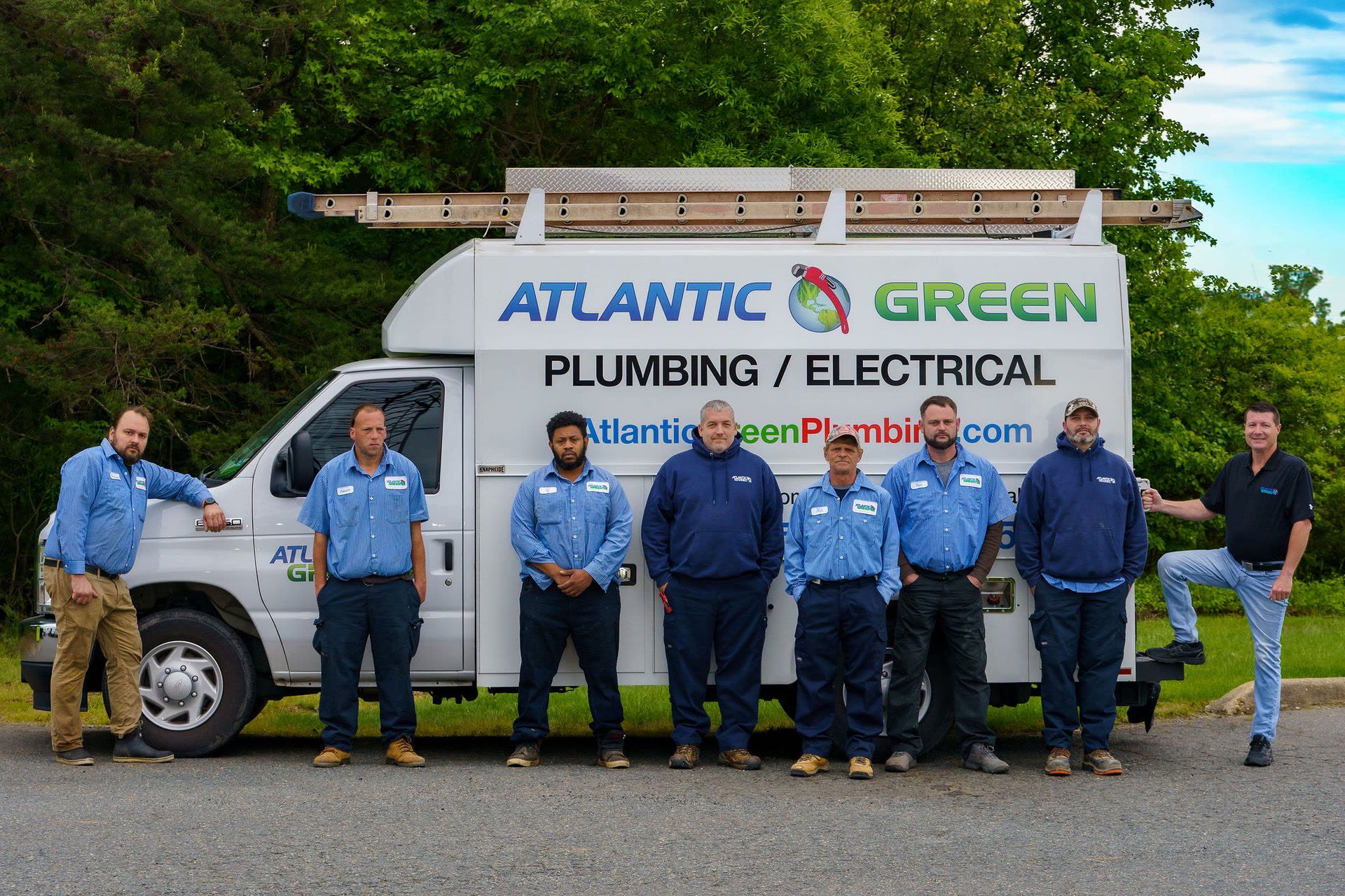 The Atlantic Green crew in blue uniforms standing in front of a white Atlantic Green Plumbing / Electrical service truck